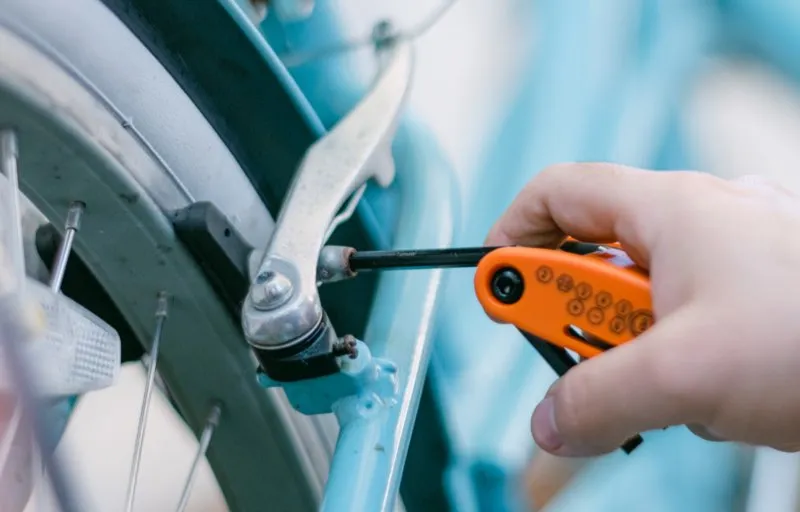 A mechanic adjusting a brake caliper with a multi-tool